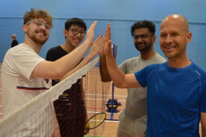 Four members high-fiving over the net at a club night